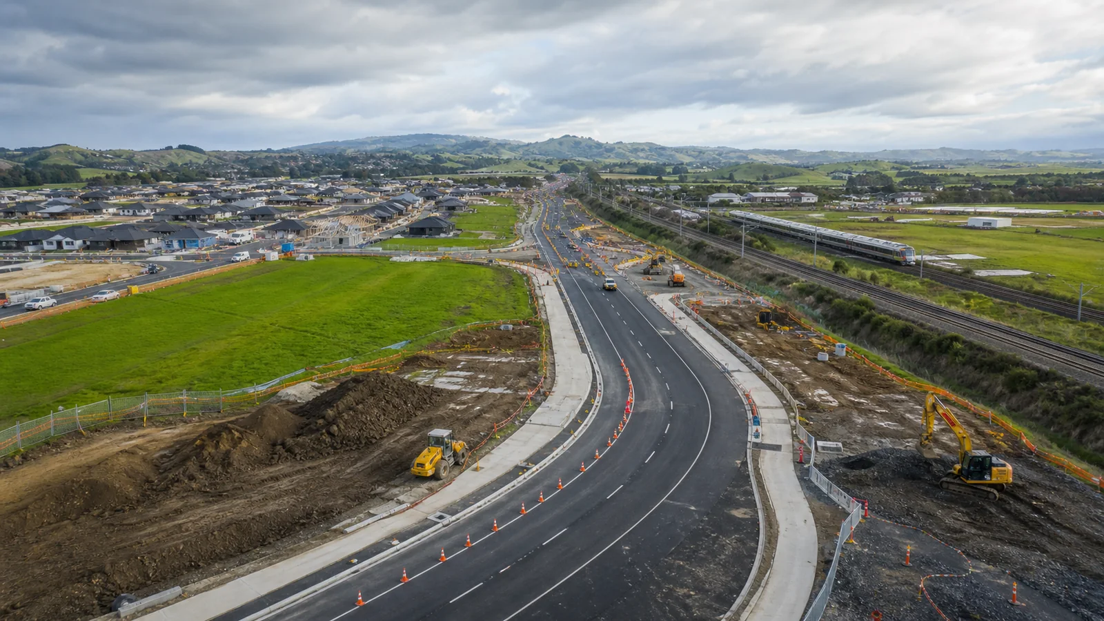Greenfield growth corridor with new housing earthworks, road widening and traffic cones