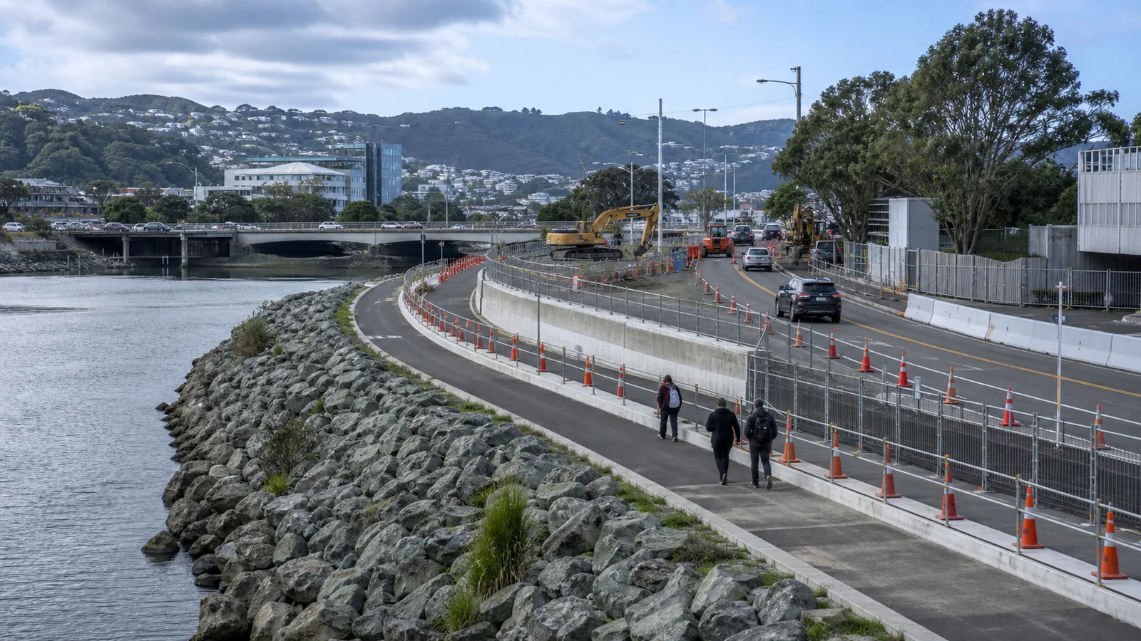 River adjacent urban road works corridor with temporary traffic controls and bridge infrastructure works